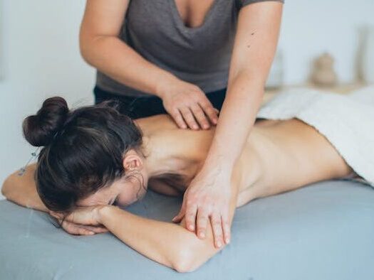 Woman Lying on Bed While Having A Massage